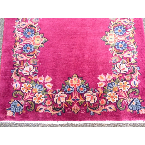 172 - A Persian rug, decorated with a floral border, on a red ground  77