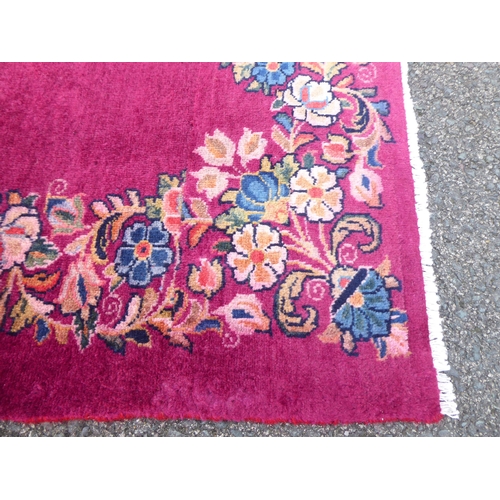 172 - A Persian rug, decorated with a floral border, on a red ground  77