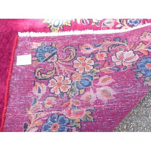 172 - A Persian rug, decorated with a floral border, on a red ground  77