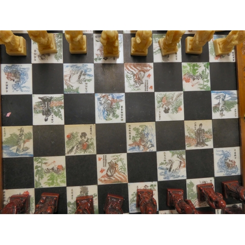 204 - A Oriental style resin chess set, in a fold-out board carrying case, set dragon carved carrying case... 