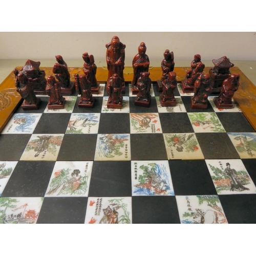 204 - A Oriental style resin chess set, in a fold-out board carrying case, set dragon carved carrying case... 