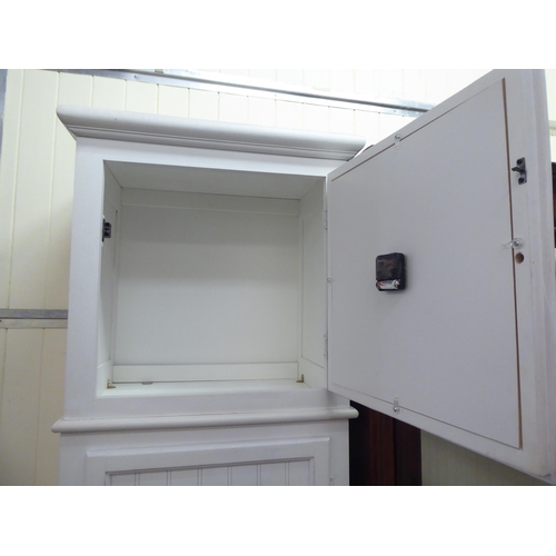 30 - A modern white painted cabinet, fashioned as a longcase clock with two doors, raised on square, tape... 