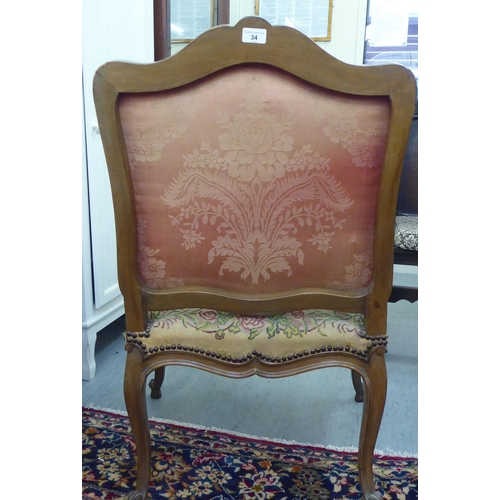 34 - An overpainted open arm library chair, the back and seat cushions tapestry upholstered, raised on ca... 