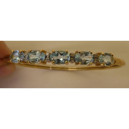 356 - A 9ct gold bangle, set with five pale blue stones, separated by diamonds