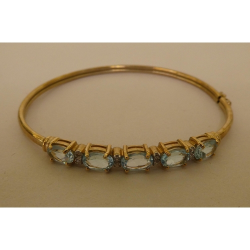 356 - A 9ct gold bangle, set with five pale blue stones, separated by diamonds