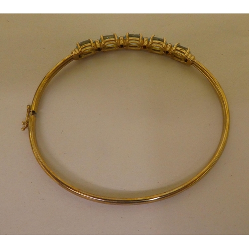 356 - A 9ct gold bangle, set with five pale blue stones, separated by diamonds