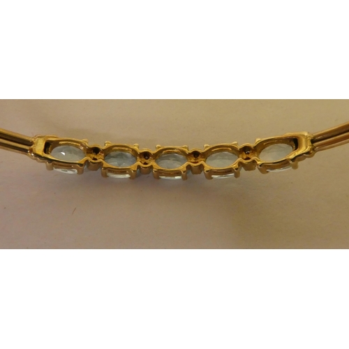 356 - A 9ct gold bangle, set with five pale blue stones, separated by diamonds