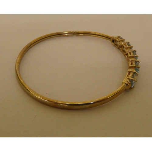 356 - A 9ct gold bangle, set with five pale blue stones, separated by diamonds