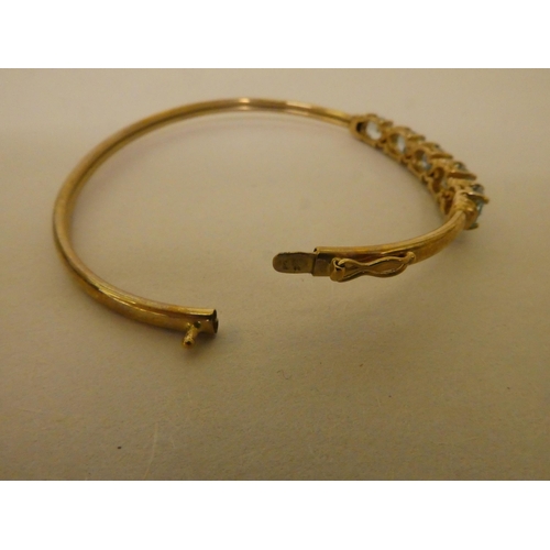 356 - A 9ct gold bangle, set with five pale blue stones, separated by diamonds