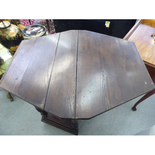 42 - A mid 20thC Gothic design oak side table with a hinged top, over a carved, panelled front, raised on... 