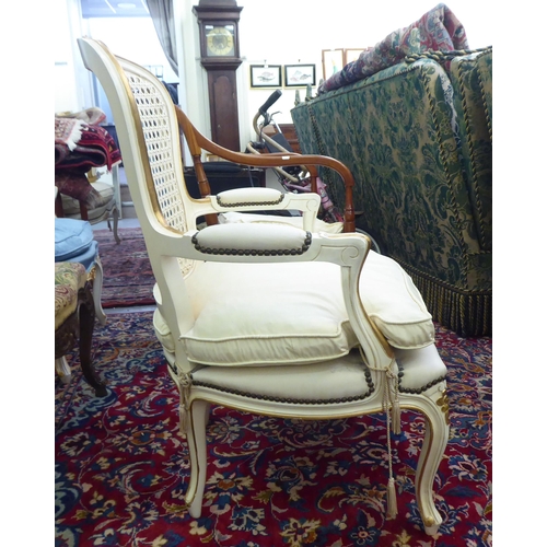 53 - A modern cream painted and upholstered bedroom chair with a caned back, raised on cabriole legs