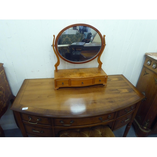 7 - A modern yew finished bowfront dressing table, raised on turned, reeded legs  30