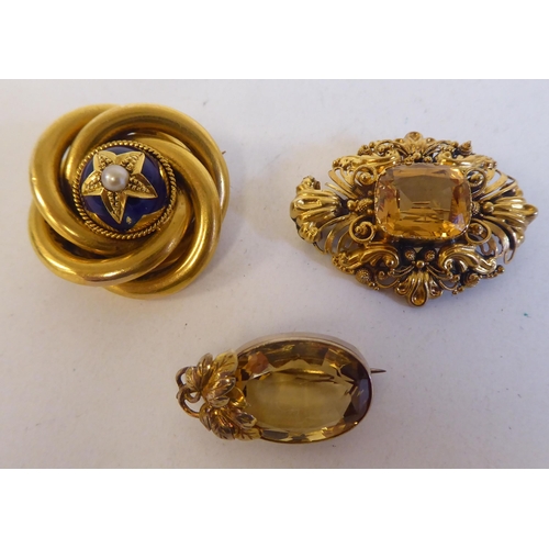 91 - Three yellow metal brooches: to include one set with a central yellow stone, surrounded by floral fi... 