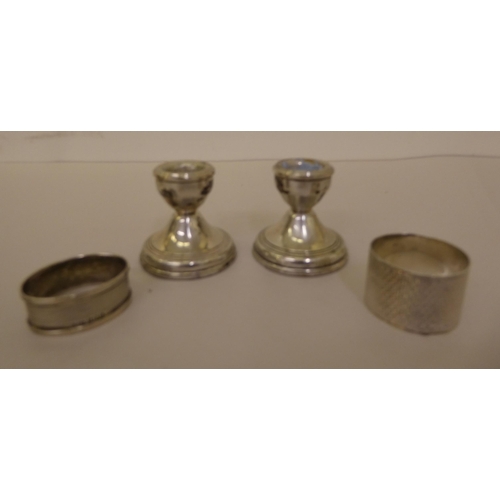 357 - Silver collectables, viz. a pair of dwarf candlesticks; and two dissimilar napkin rings  mixed ... 