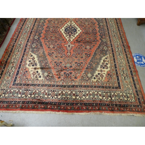 32 - A Persian woollen carpet, decorated in floral and geometric designs, on a red ground  150