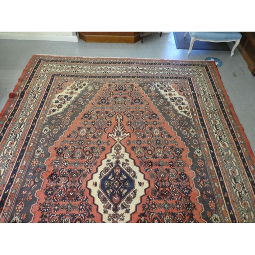 32 - A Persian woollen carpet, decorated in floral and geometric designs, on a red ground  150