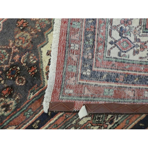 32 - A Persian woollen carpet, decorated in floral and geometric designs, on a red ground  150