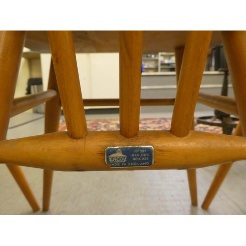 26 - A set of three Ercol beech and elm framed, curved bar and spindled back chairs, the solid seats rais... 