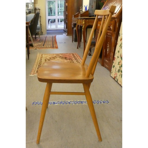 26 - A set of three Ercol beech and elm framed, curved bar and spindled back chairs, the solid seats rais... 