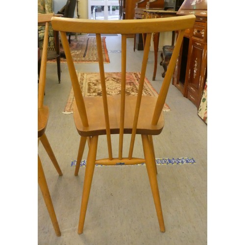 26 - A set of three Ercol beech and elm framed, curved bar and spindled back chairs, the solid seats rais... 