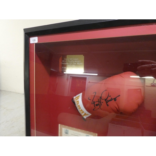 128 - A framed collage, featuring a signed Barry McGuigan boxing glove  bears a certificate of authenticit... 