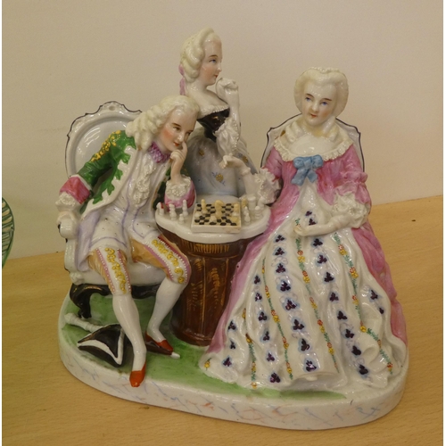 223 - A mixed lot: to include a 20thC Continental porcelain group, figures in period costume, playing ches... 