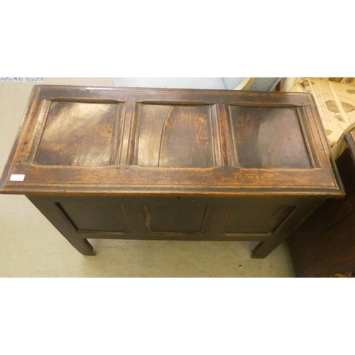 244 - A mid 18thC panelled oak coffer with straight sides and a hinged lid, raised on straight legs  ... 