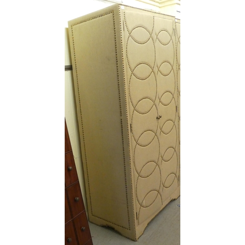 249 - A modern stud upholstered fabric, two door wardrobe, enclosing an open shelf, over a hanging rail, o... 