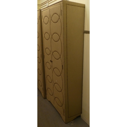 250 - A modern stud upholstered fabric, two door wardrobe, enclosing an open shelf, over a hanging rail, o... 