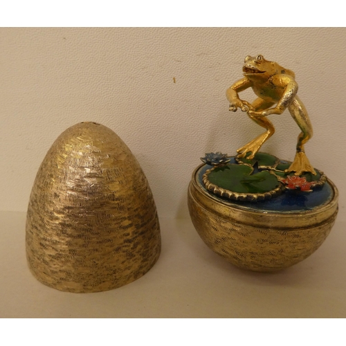 271 - A Stuart Devlin textured silver 'surprise' egg, the cover revealing a gilded and enamel frog, amongs... 