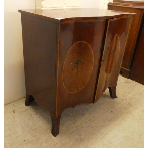 37 - An Edwardian crossbanded yew and mahogany serpentine front, two door cabinet, enclosing two open she... 