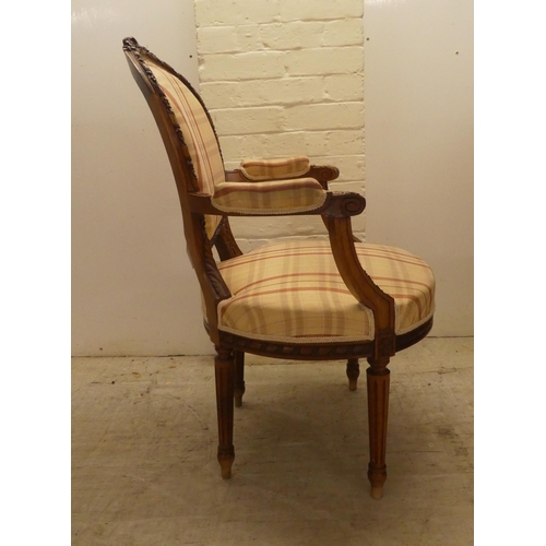 42 - A 20thC French inspired, carved mahogany framed open arm salon chair, raised on fluted forelegs