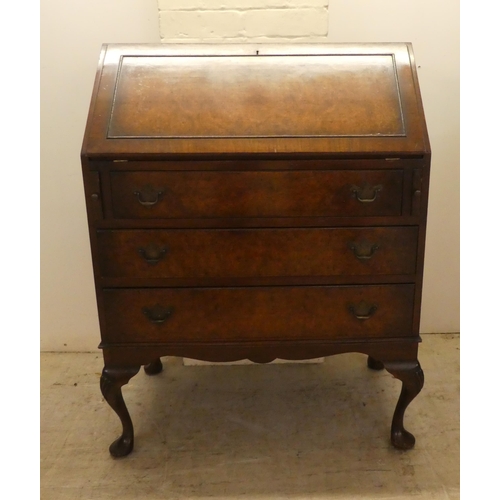 47 - A 1930s burr walnut finished bureau, the fall-flap over three drawers, raised on shell carved cabrio... 