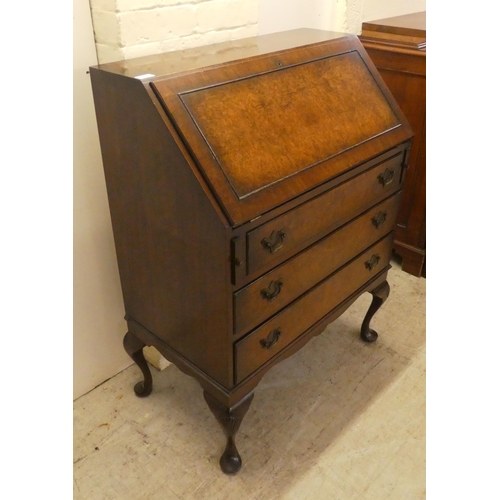 47 - A 1930s burr walnut finished bureau, the fall-flap over three drawers, raised on shell carved cabrio... 