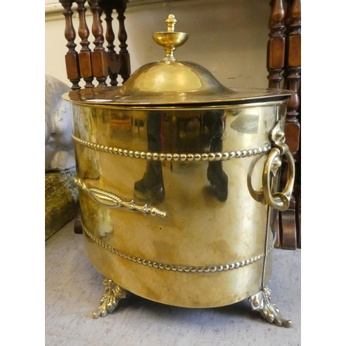 218 - An early 20thC polished brass, oval lidded, twin handled coal bin, on splayed foliate design feet  1... 