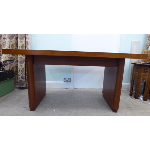 115 - A circa 1960/70s teak one-piece desk with two drawers, raised on two lozenge shaped pedestals  31