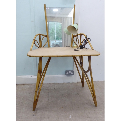 119 - A circa 1960/70s cane bound bamboo framed one-piece dressing table with a mirror, over a rattan cove... 