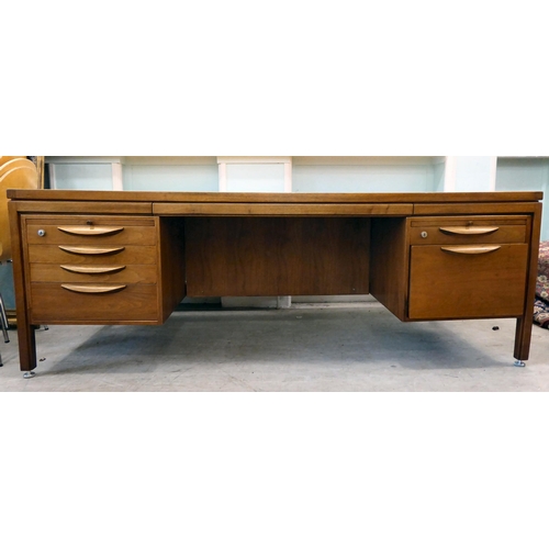 140 - A 1970s Jens Risom Design Ltd teak one piece, twin pedestal desk with an arrangement of sliding, gra... 