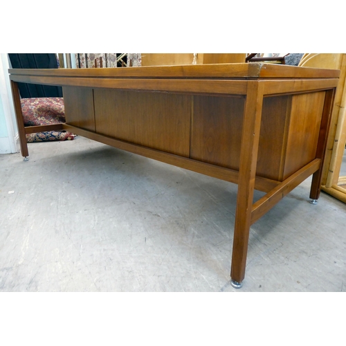 140 - A 1970s Jens Risom Design Ltd teak one piece, twin pedestal desk with an arrangement of sliding, gra... 