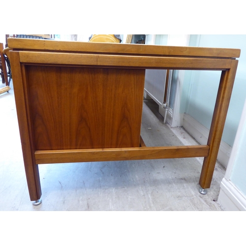 140 - A 1970s Jens Risom Design Ltd teak one piece, twin pedestal desk with an arrangement of sliding, gra... 