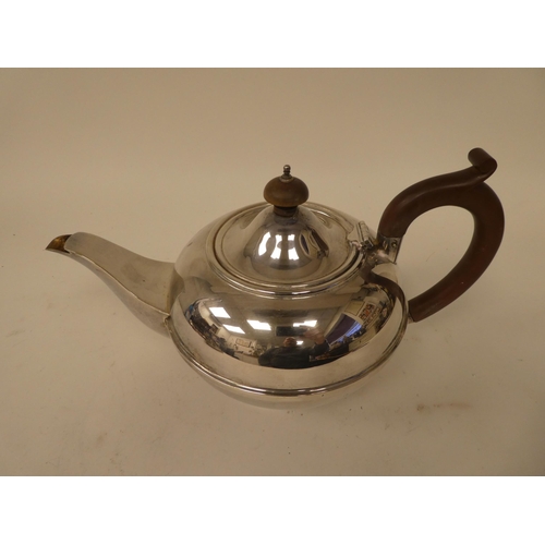 234 - A silver teapot of squat, bulbous form with a swept spout, hinged lid, insulated handle and knop, on... 