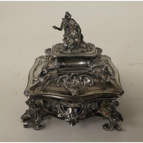 255 - A late 19thC Continental white metal jewellery casket, the hinged lid surmounted by a mother and chi... 