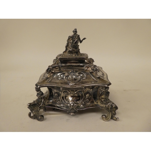 255 - A late 19thC Continental white metal jewellery casket, the hinged lid surmounted by a mother and chi... 