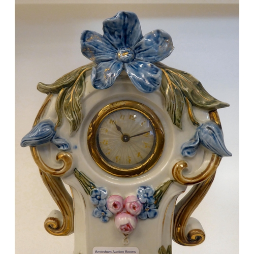 64 - A Victorian style novelty mantel timepiece, the china case featuring a couple below the floral decor... 