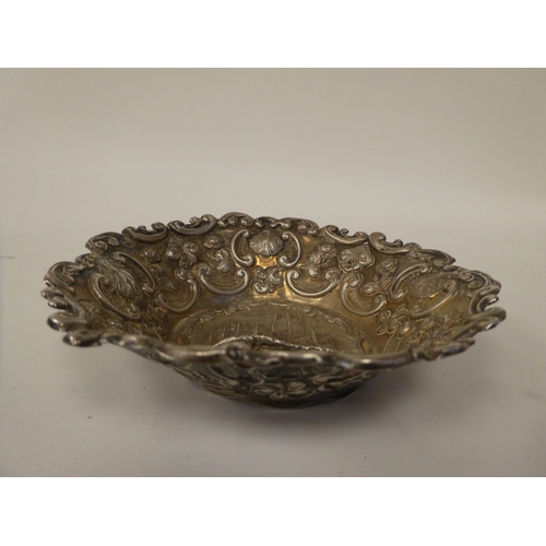 93 - A silver dish, featuring an embossed elevation of a church, the borders depicting sea scrolls, shell... 