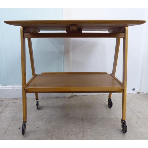 98 - A circa 1950-70s Remploy light oak drop-leaf, two tier hostess trolley, raised on straight legs and ... 