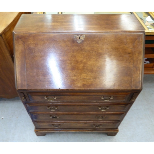 361 - A modern Georgian design oak bureau with a fall flap, over four drawers, raised on bracket feet ... 