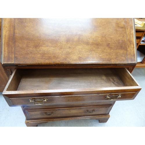 361 - A modern Georgian design oak bureau with a fall flap, over four drawers, raised on bracket feet ... 