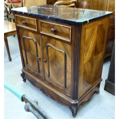 364 - A late 19thC kingswood side cabinet with a marble top, over two drawers and two doors, raised on cab... 