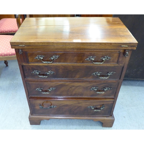 366 - An early 20thC mahogany bachelor chest with a foldover top and four long drawers, raised on bracket ... 